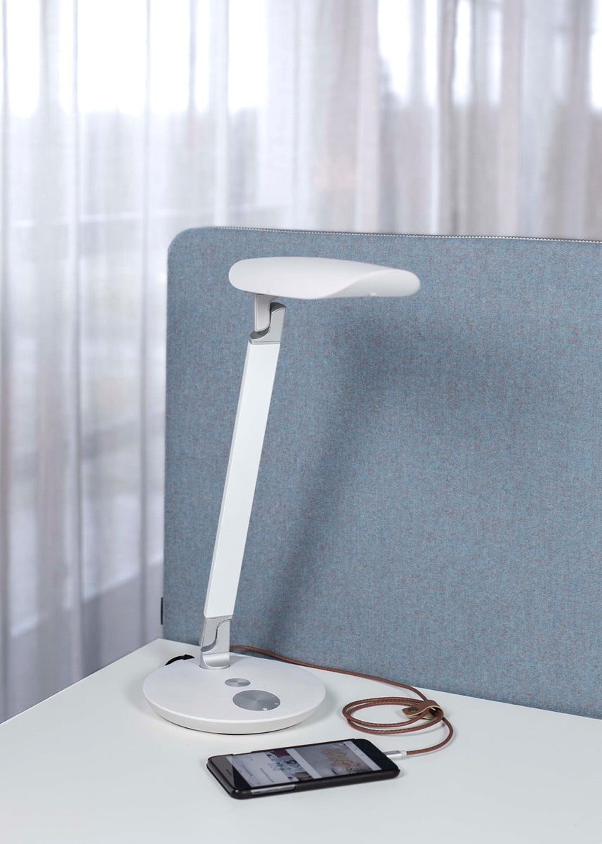 Bureaulamp Funki LED in wit naast een bureauscherm met laadkabel
