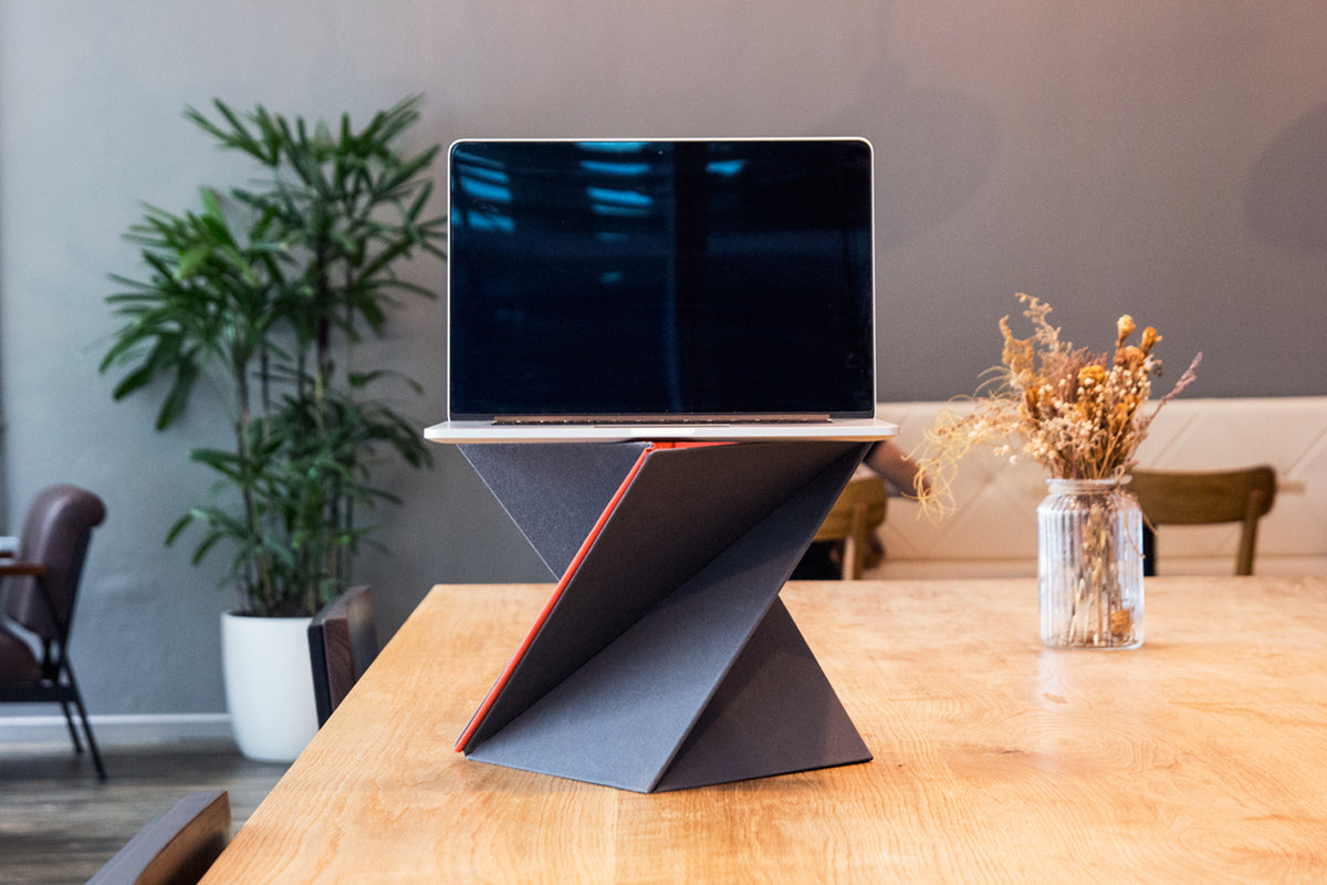 De uitgeklapte standaard met rode binnenzijde op een houten tafel, met een laptop erop