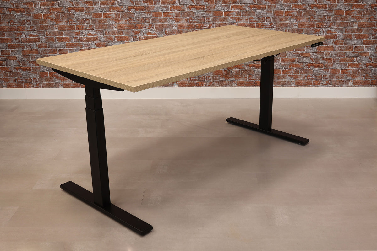 Zit-sta bureau Ciao met eikenkleurig blad op een zwart T-frame voor een bakstenen muur