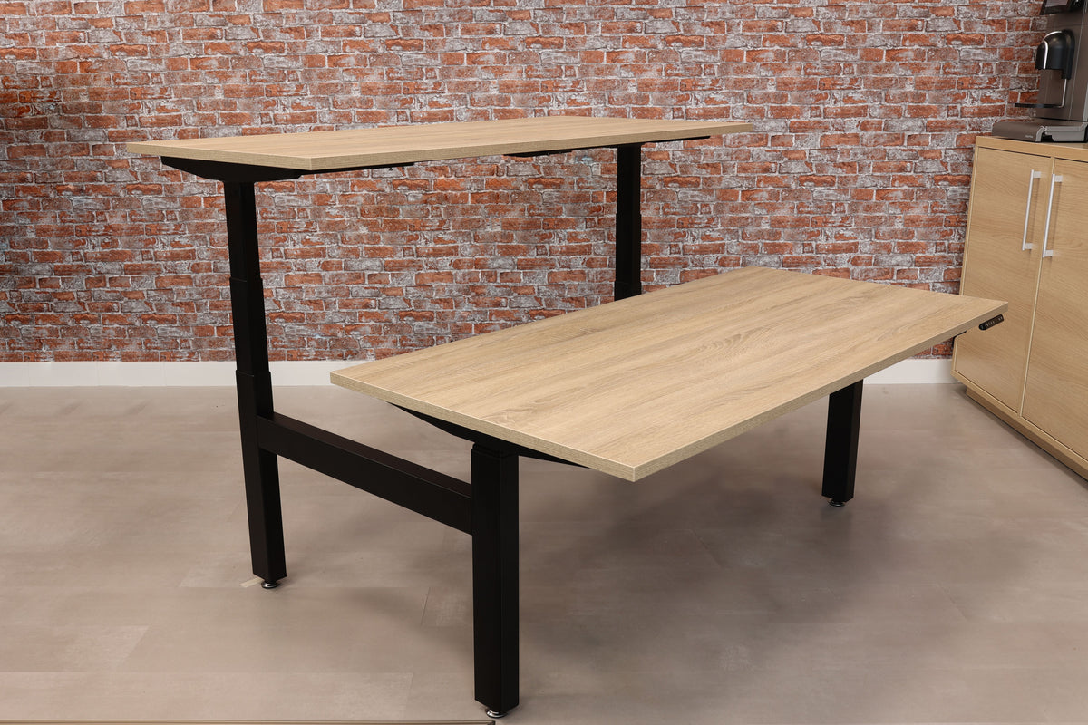 Elektrisch duo bureau Ciao met eikendecor bladen op een zwart onderstel in de showroom
