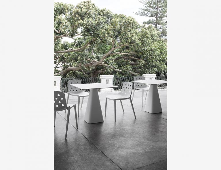 Isidora stoelen aan een tafel buiten met groen op de achtergrond