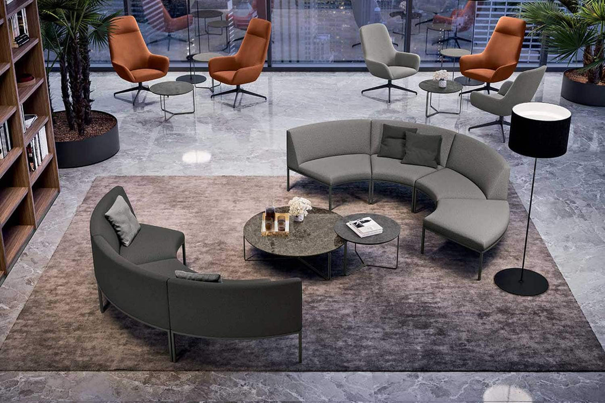 Sfeerbeeld van een lounge met lage ronde tafels tussen gebogen donkergroene banken en oranje fauteuils