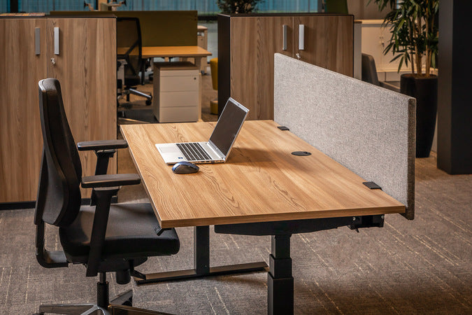 ECON akoestisch scherm in lichtgrijs op de achterrand van een zit-sta bureau met houten blad en laptop