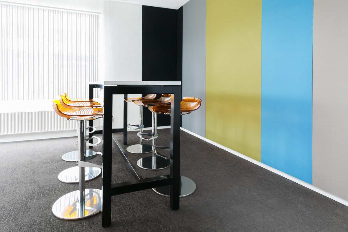 Kantoorruimte met gele en blauwe akoestische wandpanelen en een statafel met barkrukken