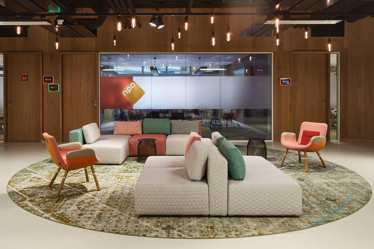M+ Sofa en fauteuils in een lounge met houten wand