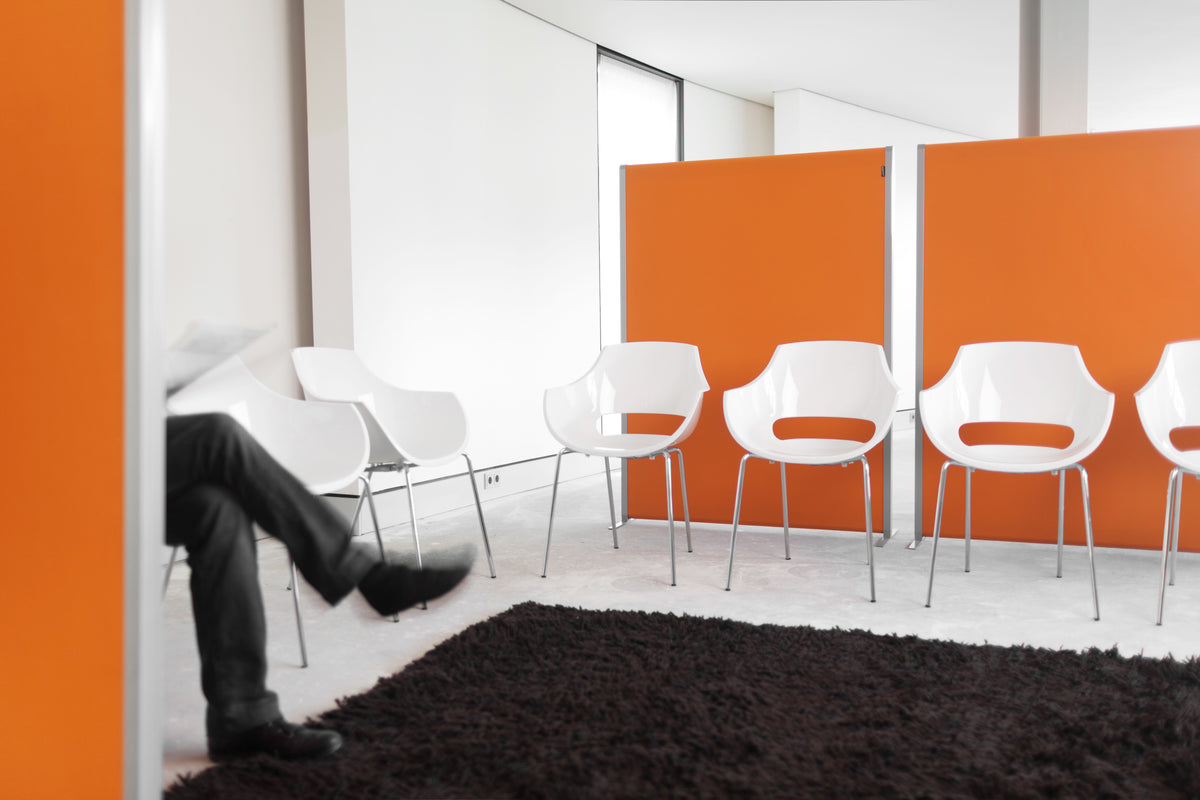 NOVU staande scheidingswanden in oranje achter witte stoelen
