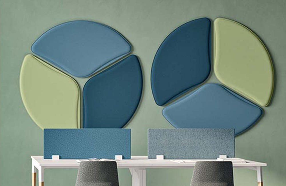 Ronde LightSound akoestische verlichtingspanelen in blauw en groen aan een groene wand boven twee werkplekken