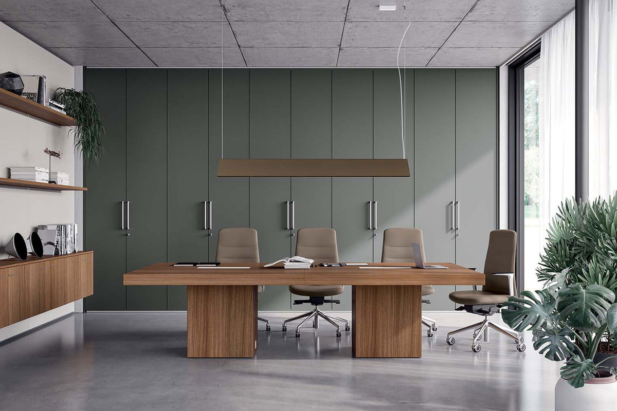 Vergadertafel in notenhout met zes lichtbruine stoelen in een vergaderruimte met groene kastenwand
