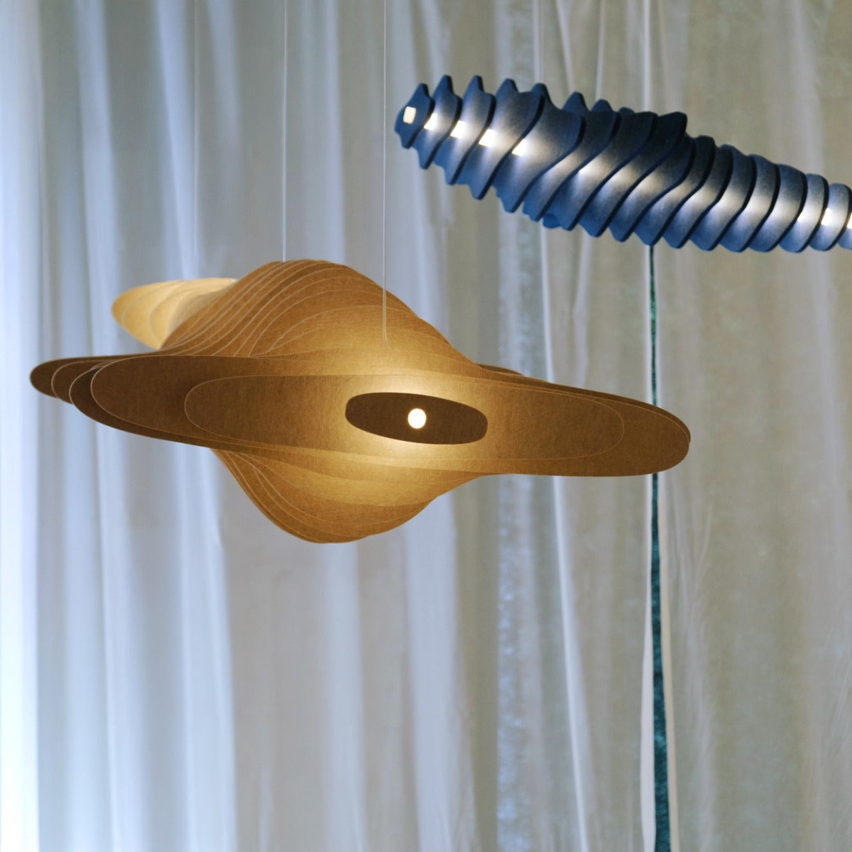 Akoestische hanglamp boven een lange vergadertafel in een lichte ruimte