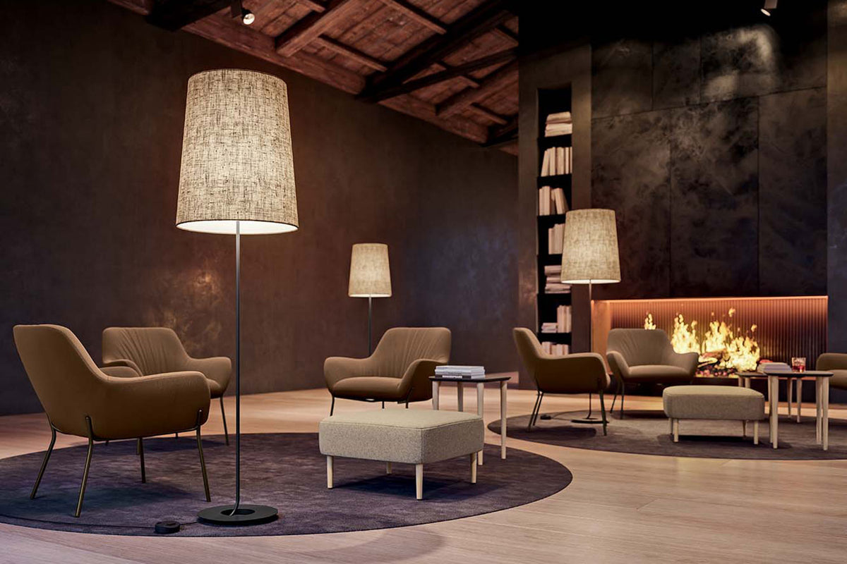 Twee staande lampen met linnen kap in een loungeruimte met fauteuils