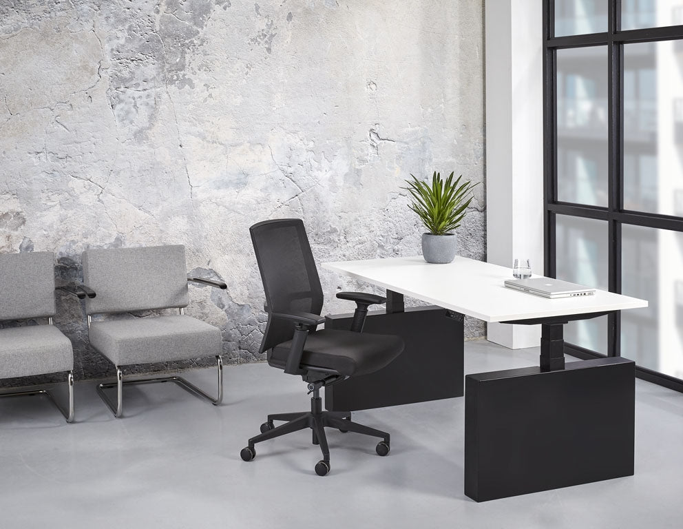 Bureau Lola met wit blad en zwarte dichte zijwang in een kantoor, met bureaustoel en fauteuils