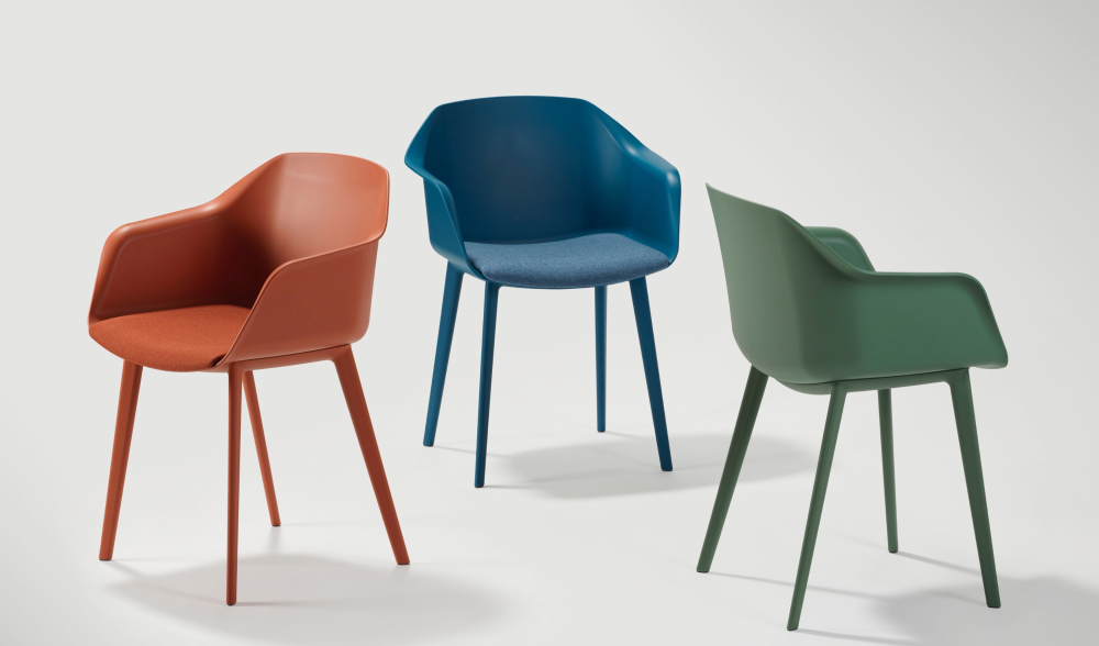 Drie Amber stoelen naast elkaar in oranjerood, blauw en groen, elk met kuip en poten in dezelfde kleur