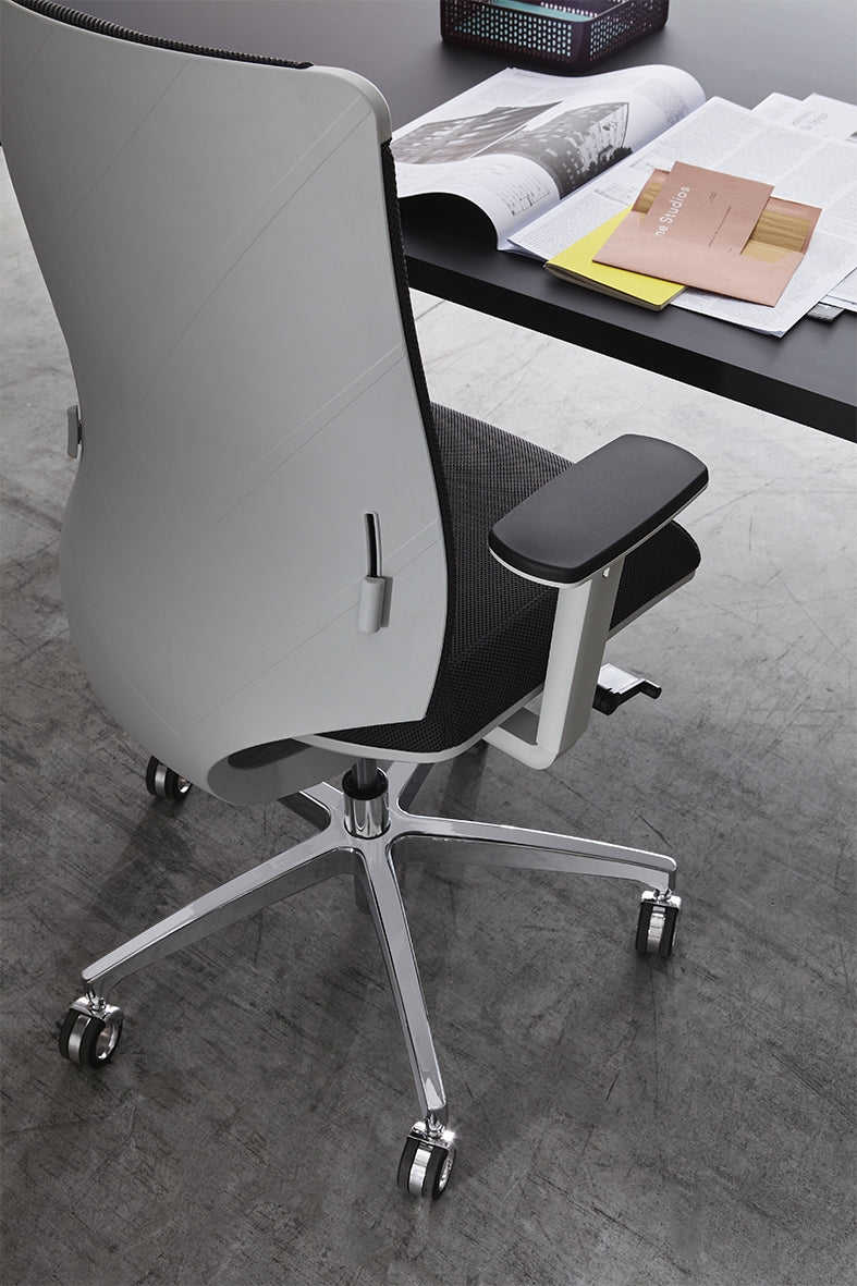 Achterzijde van de Leaf in zilvergrijs aan een bureau, met de bladvorm van de rugleuning in beeld