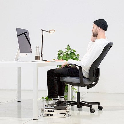 Man aan een bureau die achterover leunt op de Skate Synchro