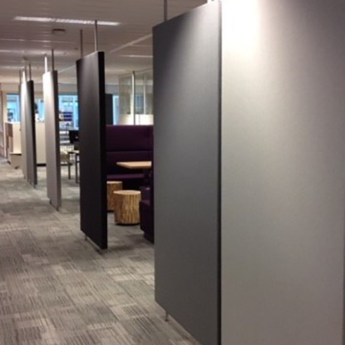 Hoge antracieten roomdividers als vrijstaande panelen in een kantoorruimte met tapijt en loungehoek