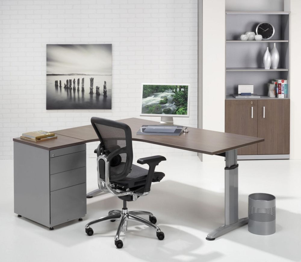 Het bureau in een kantoor met kastenwand, wandfoto, monitor en een ladeblok naast het blad