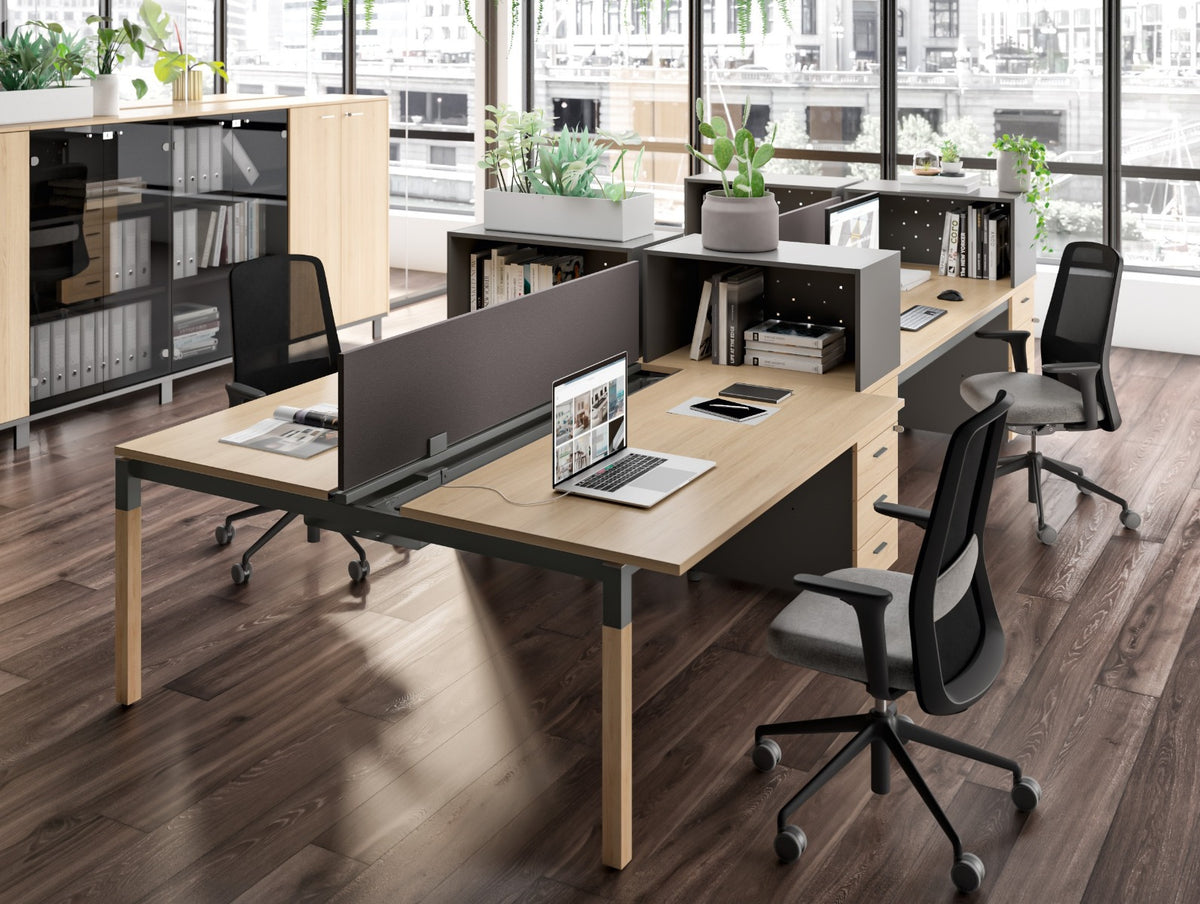 Sfeerbeeld van X4 benchwerkplekken met licht houten bladen, houten poten en donkere scheidingsschermen