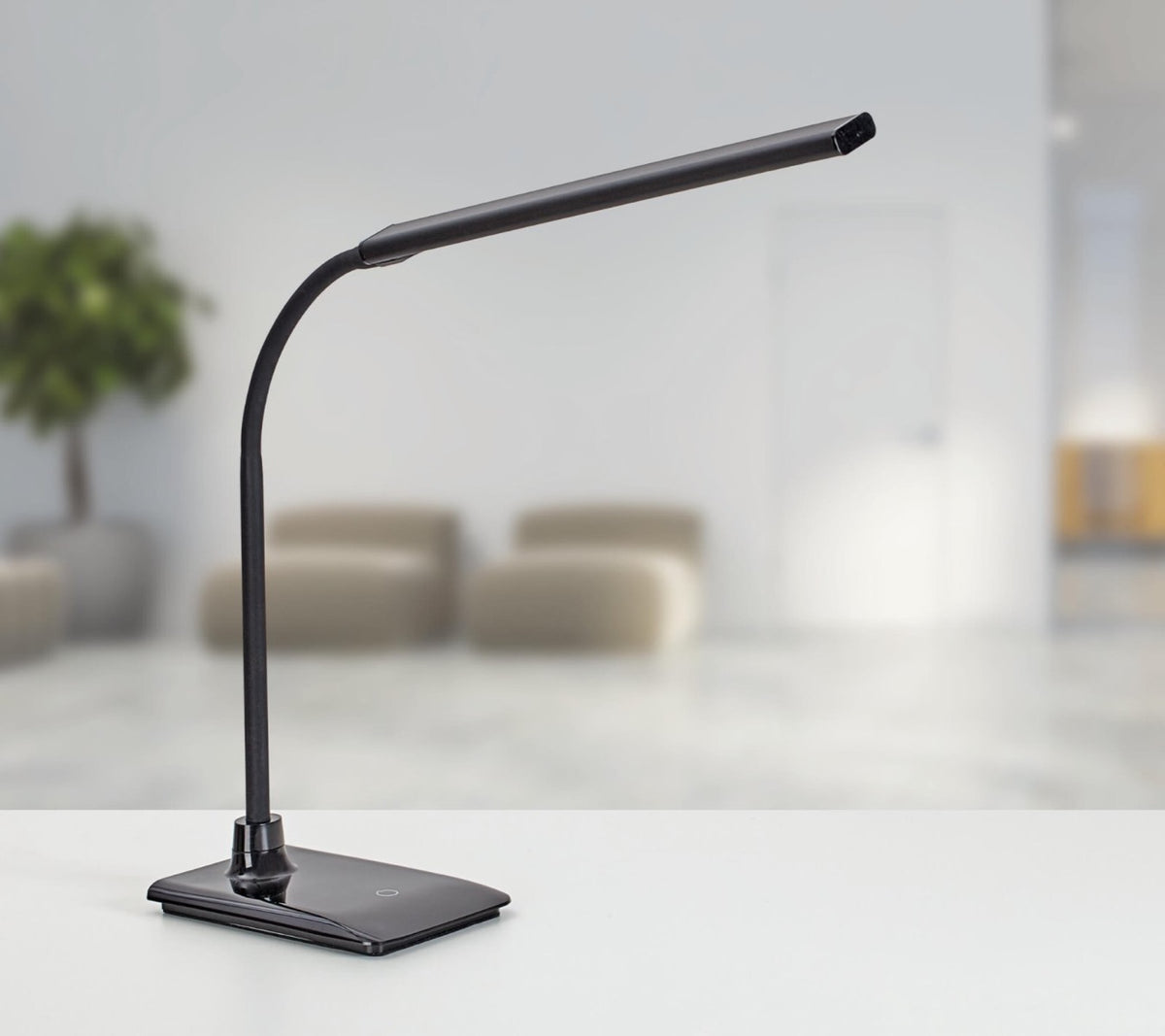 Bureaulamp Pir LED in zwart met voet op een bureau in een loungeruimte