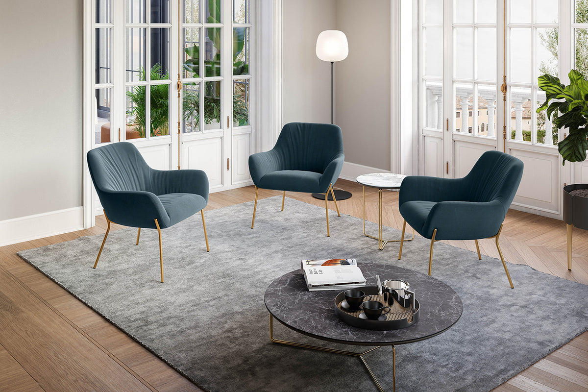 Sfeerbeeld van een zitgroep met petrolblauwe kuipstoelen op gouden poten rond een ronde salontafel