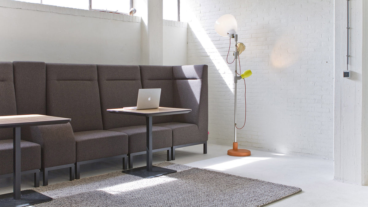 Donkerbruine loungebank met hoge rug en een bijzettafel bij een raam