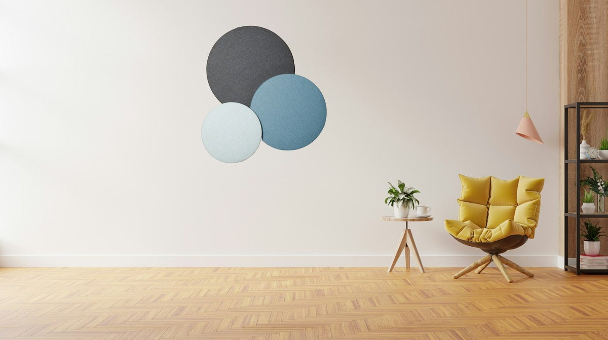 Sfeerbeeld van ronde CIRA akoestische panelen in donkergrijs en twee tinten blauw aan een lichte wand