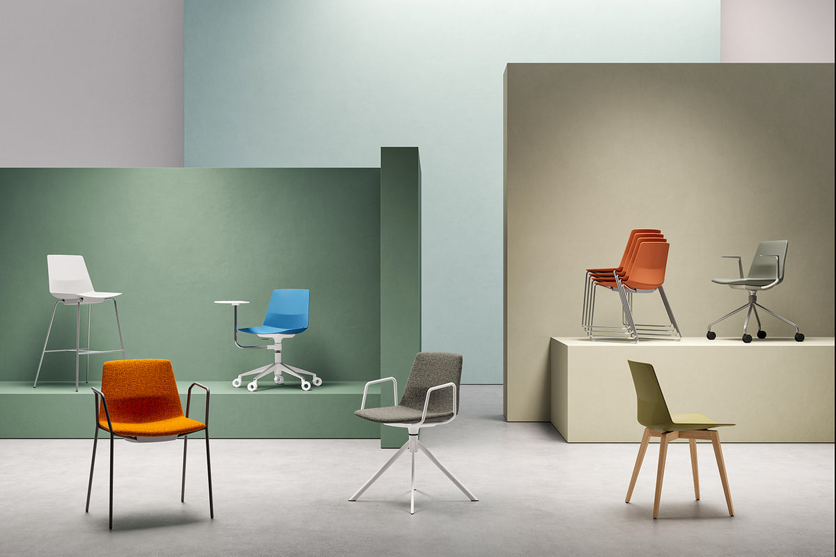 De collectie in één opstelling: een witte barkruk met voetring naast stoelen in oranje, blauw, grijs en olijfgroen