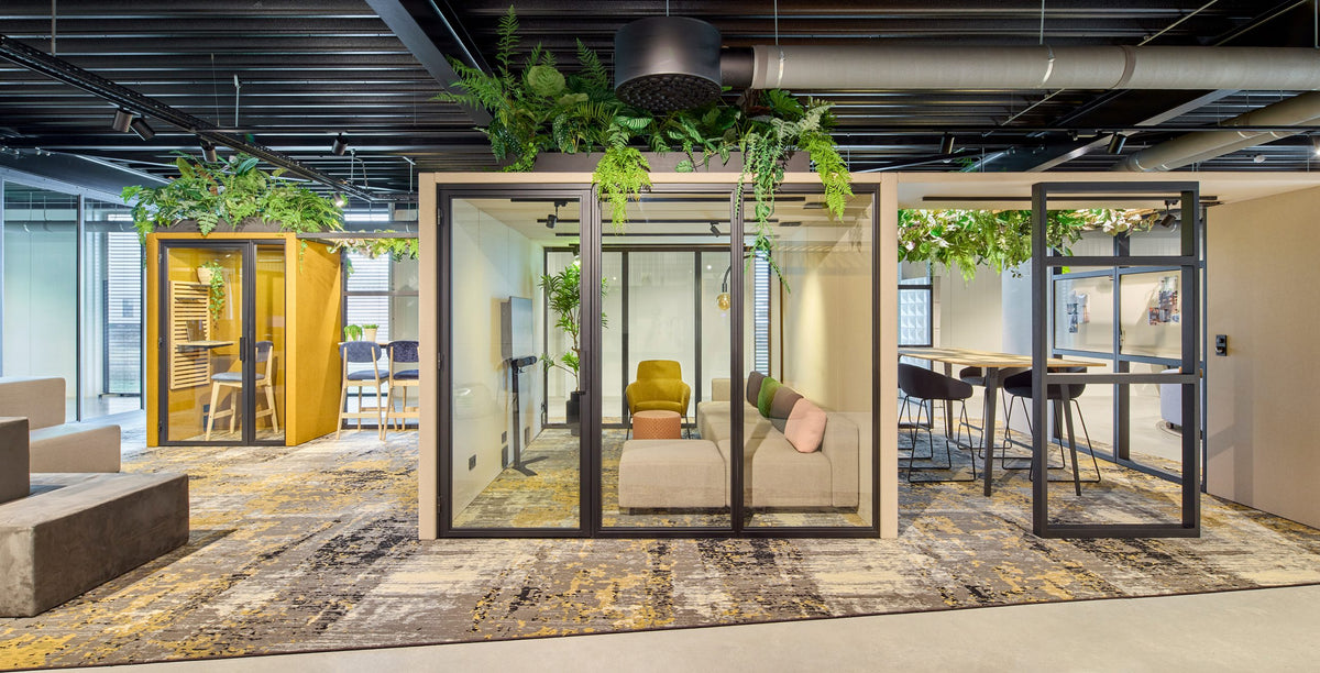 Kantoorvloer met glazen overlegcabines, planten op het dak en een zithoek ernaast