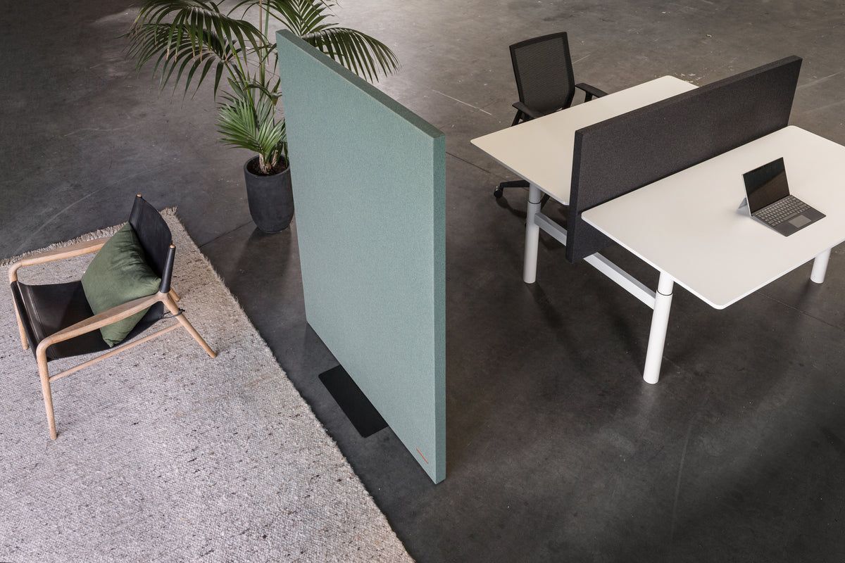 MUTE akoestische wand in groen naast een werkplek met zit-sta bureau