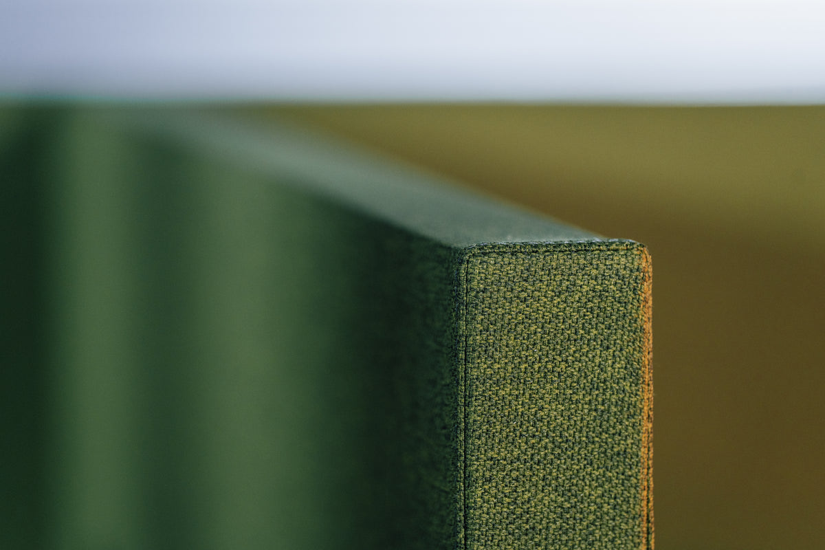 Close-up van de zijkant van een groen akoestisch paneel, met de stofstructuur en de afgewerkte rand