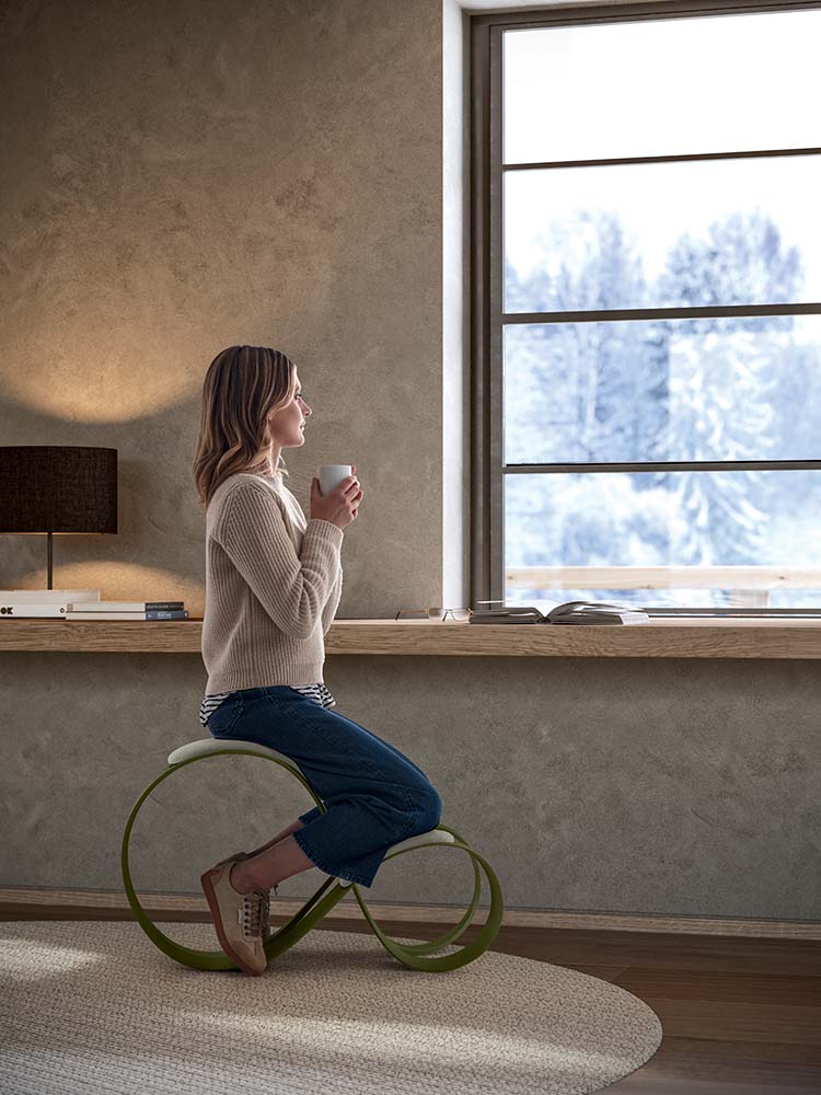 Vrouw op een Moon stoel aan een bureau bij een raam