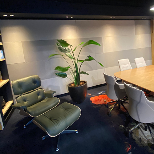 Akoestische wandpanelen in een ruimte met plant en fauteuil