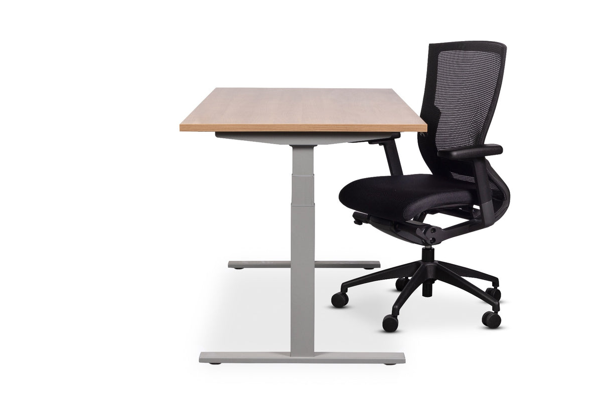 Elektrisch zit-sta bureau met houten blad op een zilverkleurige T-poot, met zwarte bureaustoel met mesh rug