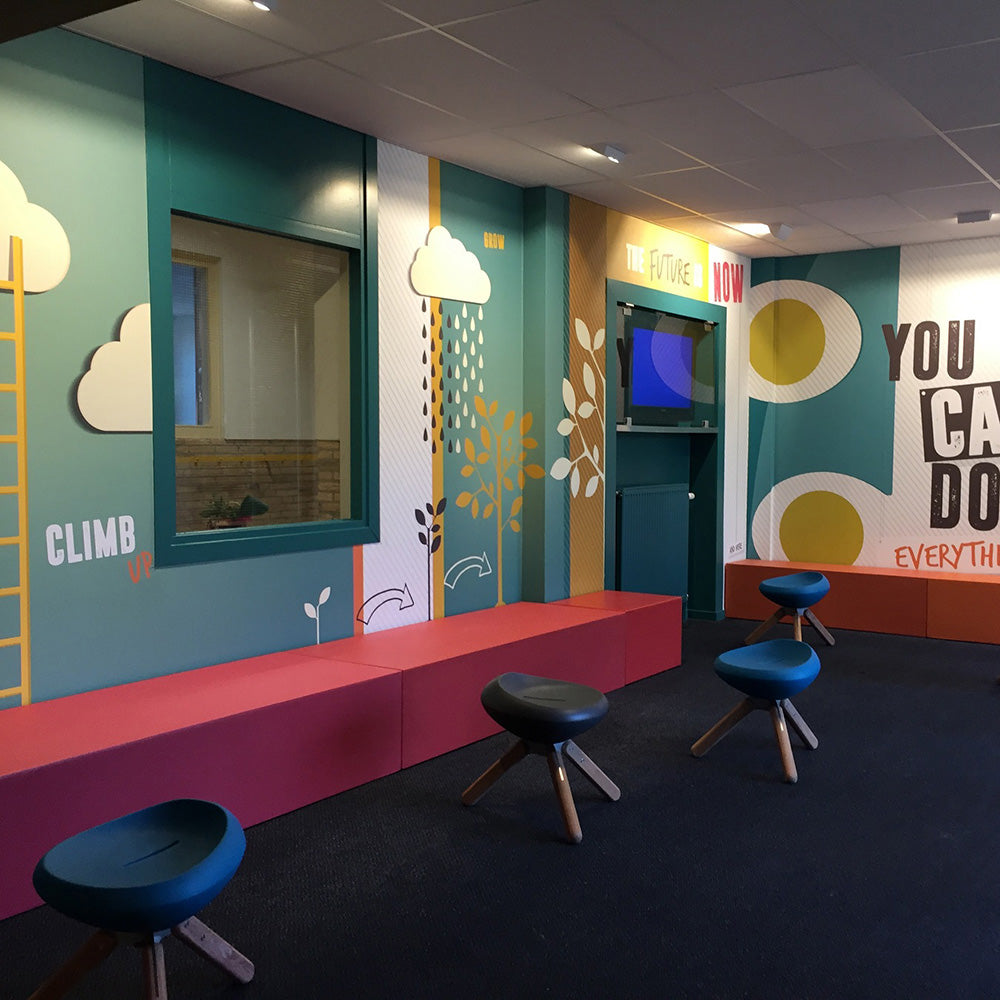 Coated bank in rood langs een wand met blauwe krukken