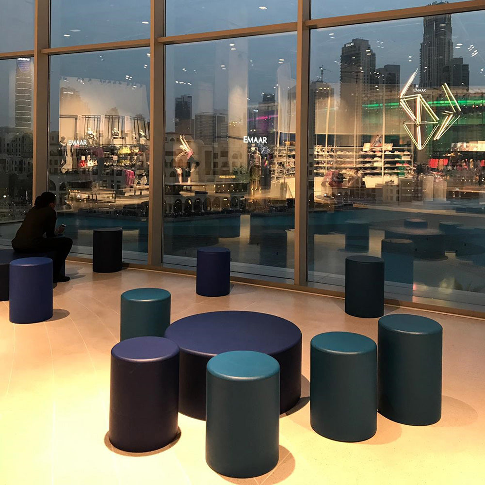 Ronde Coated poefs in een donkere lounge met uitzicht
