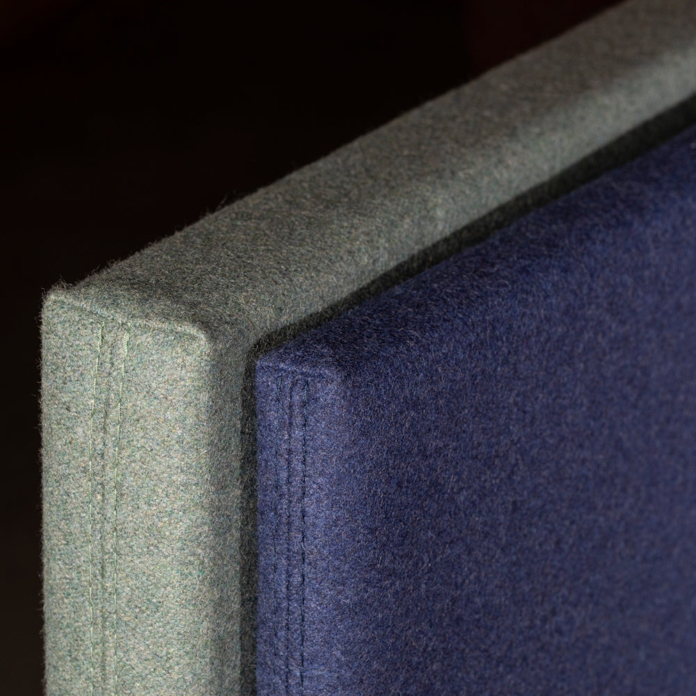 Close-up van twee akoestische schermen: grijsgroene zijkant en donkerblauw vlak met stiksel langs de rand