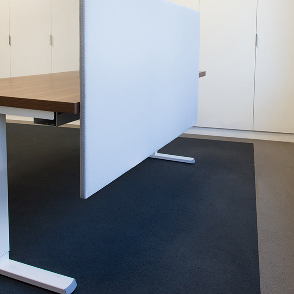 Lichtblauw akoestisch scherm naast een bureau met witte poot in een kantoor met donkerblauwe vloer