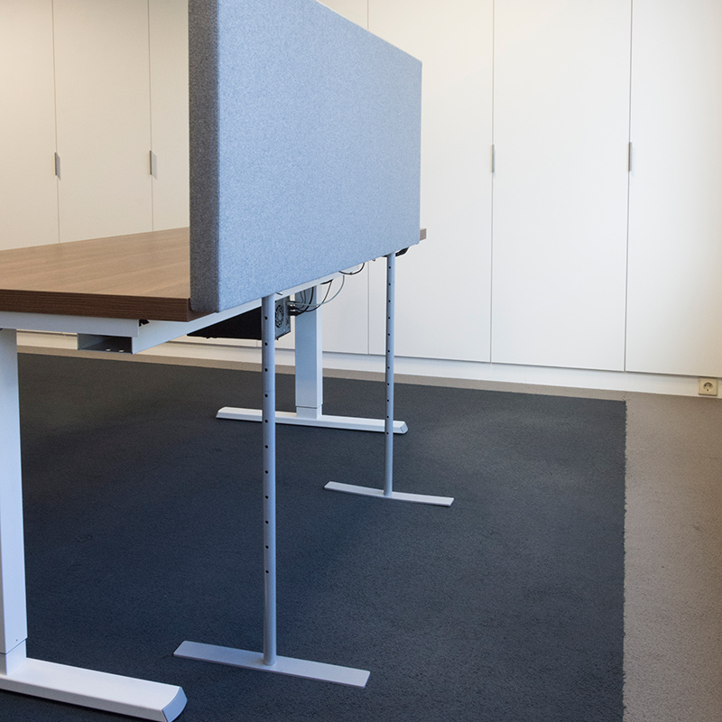 Goalpost wand: lichtblauw akoestisch scherm naast een bureau, op twee witte T-poten tot op de vloer