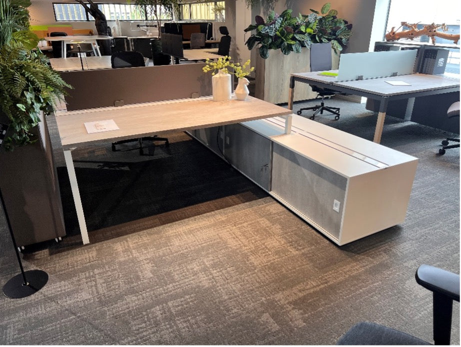 Vierpoots bench in L-opstelling met lichtgrijs werkblad, witte poten en een lage witte aanbouwkast