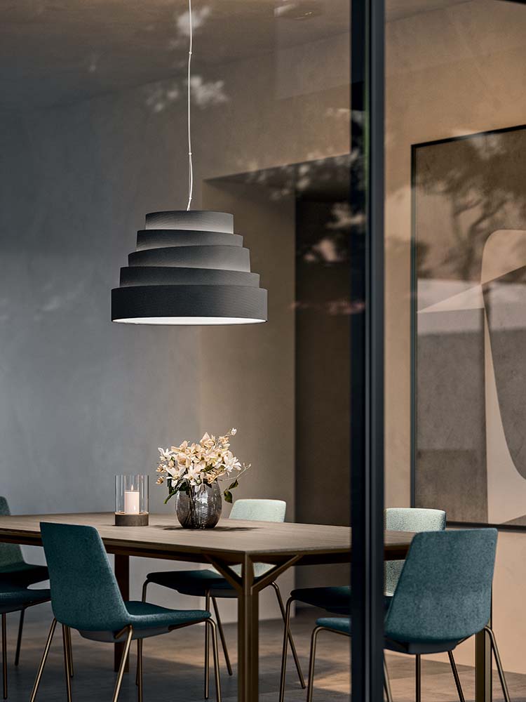 Twee zwarte hanglampen met getrapte kap boven een eettafel
