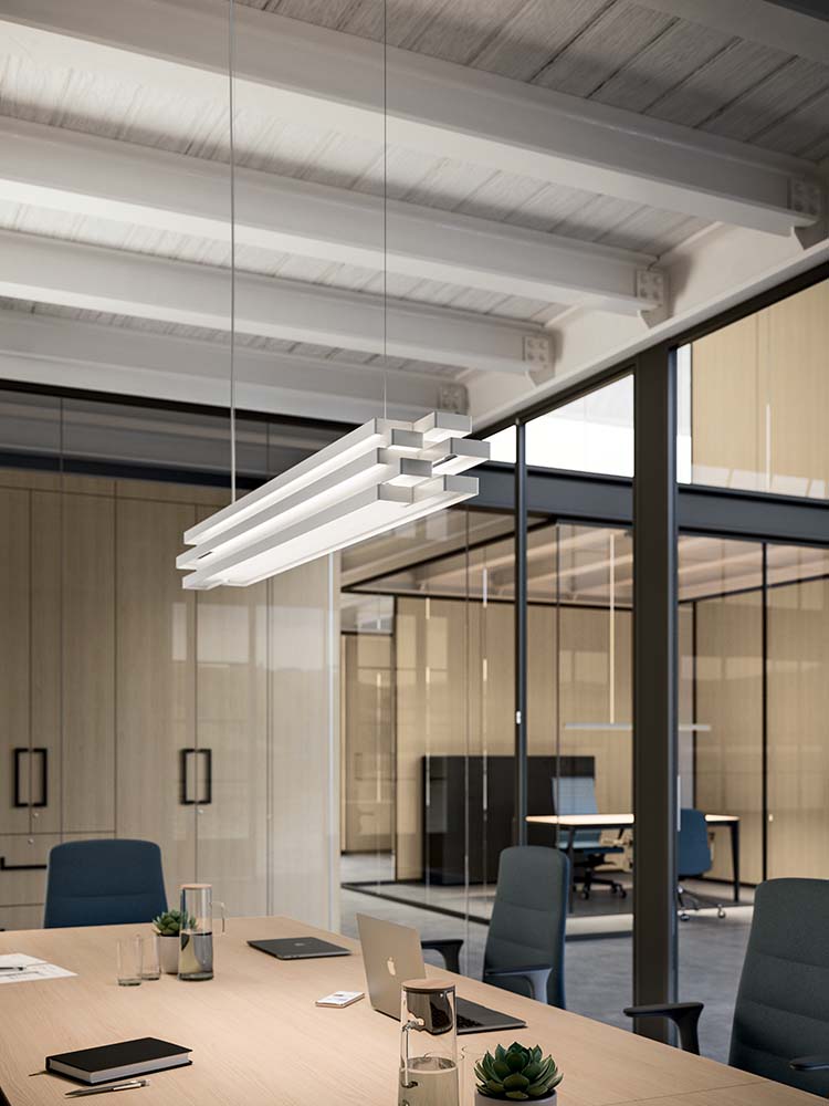 Langwerpige hanglamp met gelaagde banen boven een vergadertafel