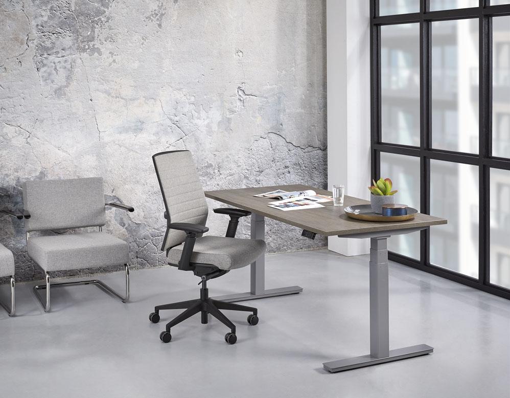 Bureau Lola met eikendecor blad en grijs onderstel naast een bank