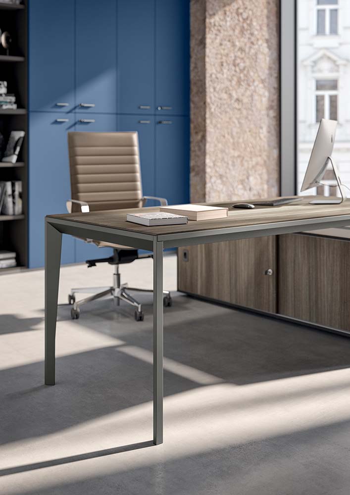 Bureau met blad in grijsbruin houtdecor op slanke metalen poten, voor een blauwe wandkast