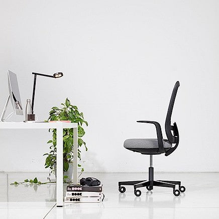 Sfeerbeeld van de Skate Synchro bureaustoel met zwarte mesh rug bij een wit bureau met planten