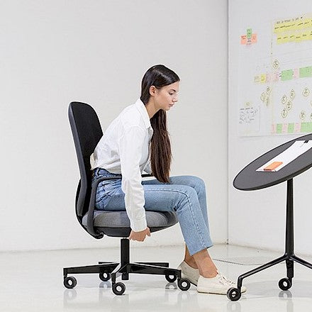 Vrouw zittend op de Skate Synchro in een overlegruimte met whiteboard
