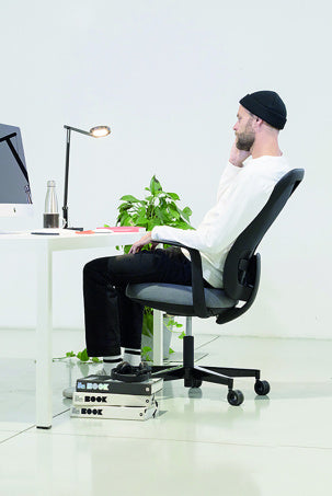 Man aan een bureau die achterover leunt op de Skate en de rug laat meebewegen
