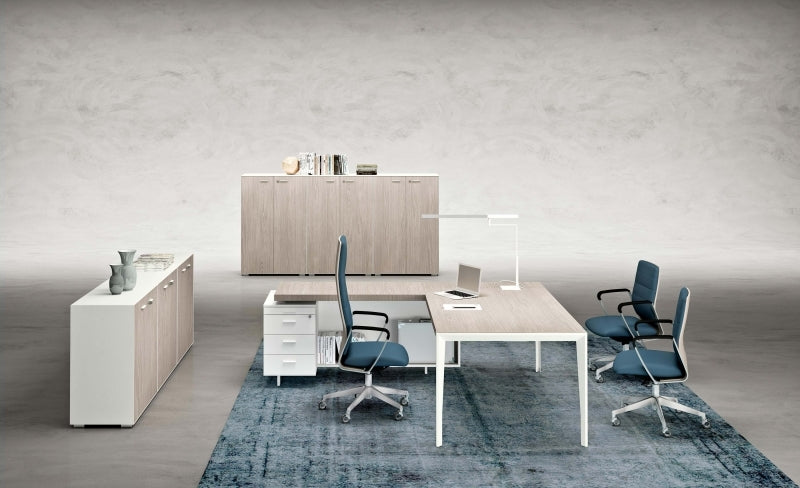 Werkplek met licht blad op witte poten, blauwe stoelen, ladeblok en dressoir op blauw tapijt