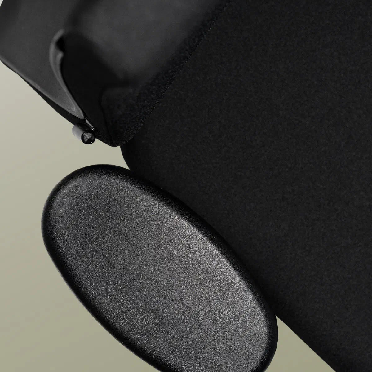 Close-up van de zachte zwarte armlegpad, met de rugleuning van de stoel er schuin achter