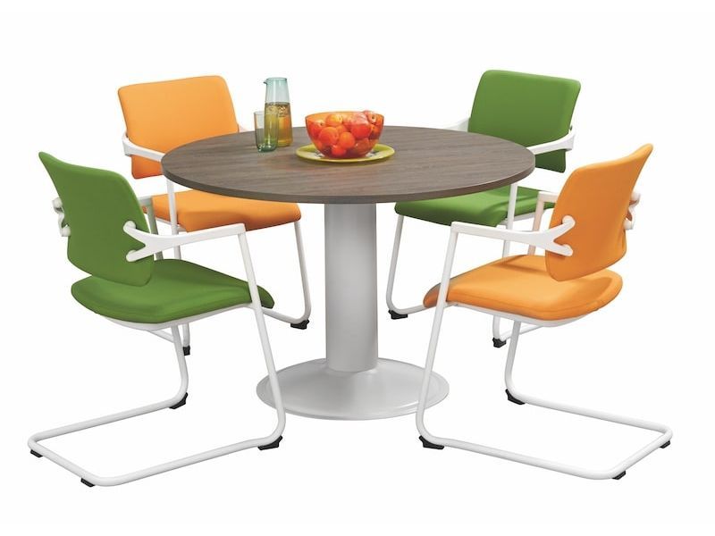 Vier kuipstoelen in groen en oranje rond de tafel, met fruitschaal en fles op het blad