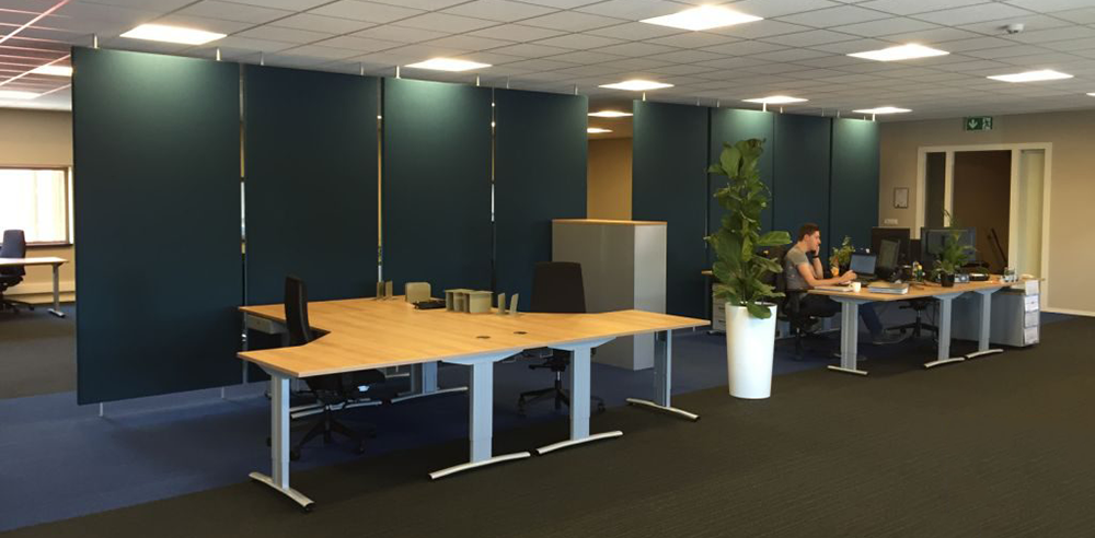 Roomdividers in groen rond werkplekken in een kantoortuin