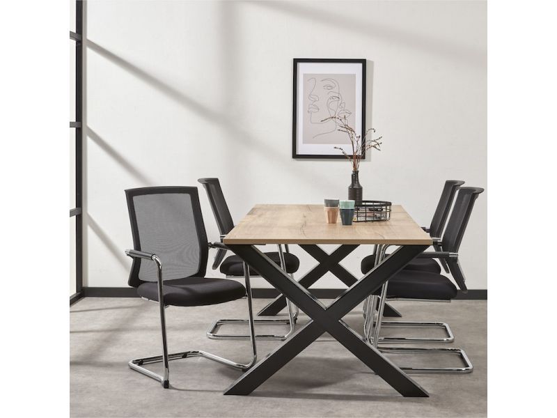 Sfeerbeeld met vier zwarte netstoelen aan de tafel, voor een lichte wand met ingelijste print